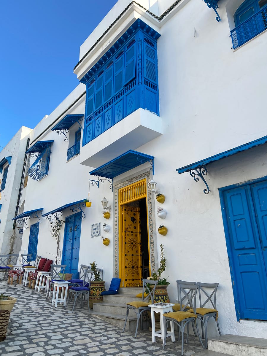 Calle empedrada de Sidi Bou Said con una puerta amarilla en una casa tradicional de Túnez.