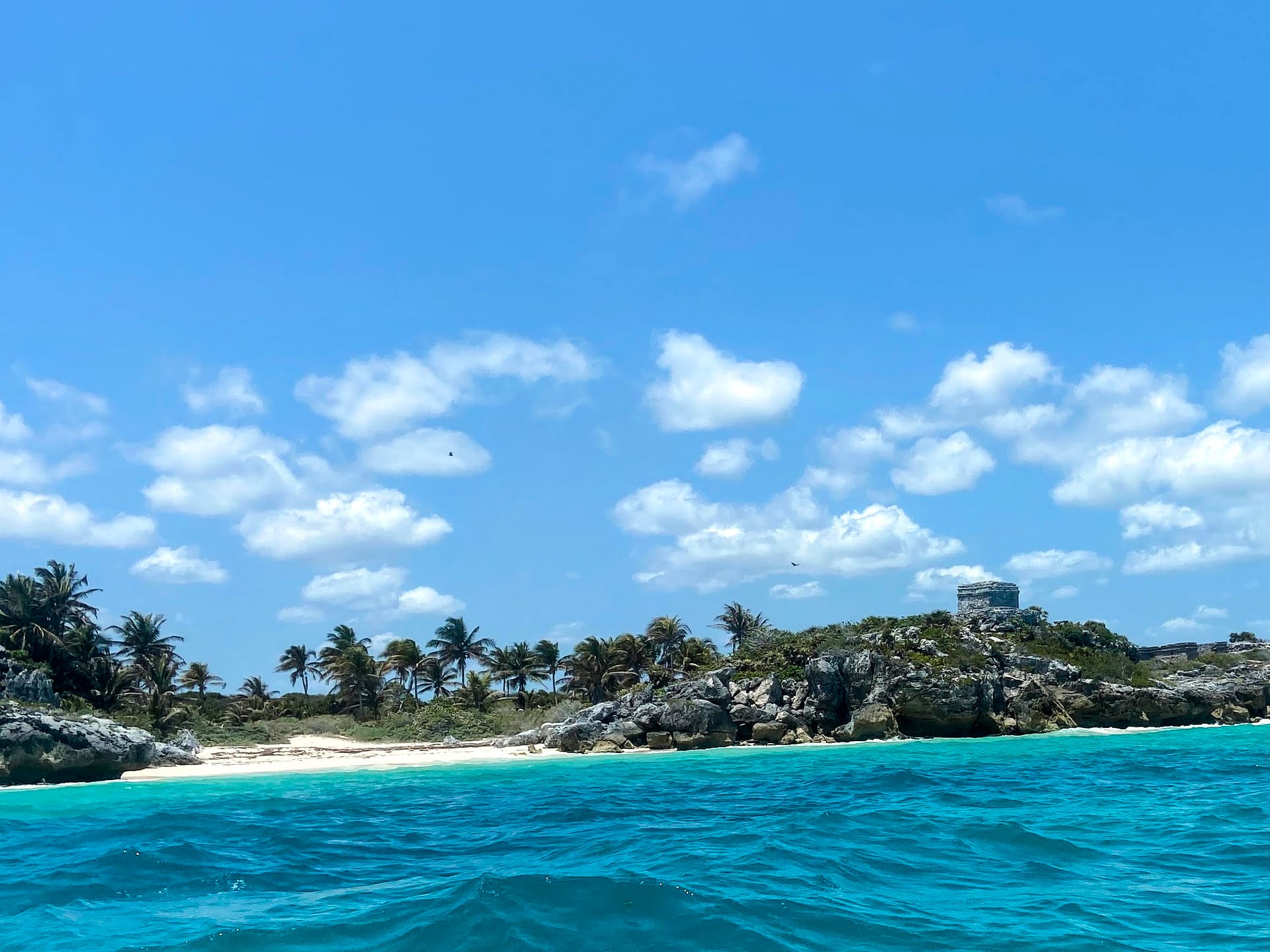 Vista de las ruinas de Tulum desde el mar con playa y templo maya Ruinas de Tulum vistas desde el mar Caribe con un templo sobre el acantilado y la playa debajo
